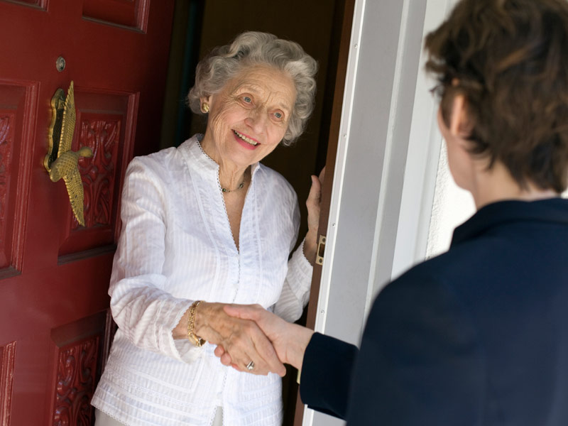 Eine alte Dame begrüßt Besuch an der Wohnungstür